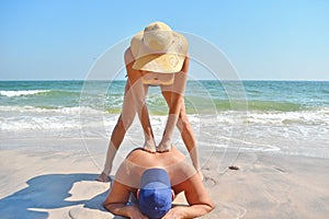 Erotic massage on beach. Girl in swimsuit getting massage. Girl masseuse on sea. Beautiful woman in bikini massaging body of man.