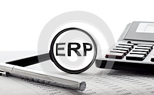 ERP concept. Magnifier glass with text on chart with pen and calculator