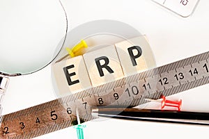 ERP - Enterprise Resource Planning on wooden cubes near a measuring ruler, magnifying glass, calculator