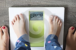 Error message on bathroom scale display, obese child weighting under parentâ€™s supervision