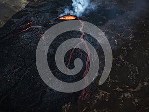 Erupted volcano and surroundings, boiling lava flowing, pull away drone shot