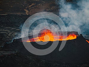Erupted volcano and surroundings, boiling lava flowing, pull away drone shot photo