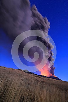 Eruzione Etna durante vista all\'alba con grandi emissioni di cenere dal cratere della cima del vulcano nel cielo azzurro