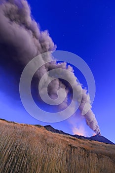 Eruzione Etna durante vista all\'alba con grandi emissioni di cenere dal cratere della cima del vulcano nel cielo azzurro