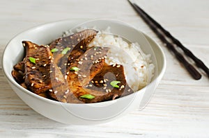 Eryngii mushroom fried with sesame and green onion and white boiled rice in a gray bowl. photo