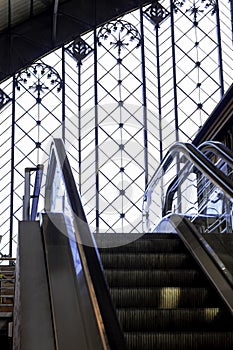 Escalator at Atocha railway Station in Madrid. Stained glass wall in the background