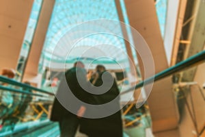 Escalator people blurred background. Interior of retail centre store in soft focus. People shopping in modern commercial