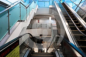 Escalator system. A guy in an empty large building descends on an escalator instead of steps