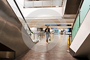 Escalator system. A guy in an empty large building descends on an escalator instead of steps