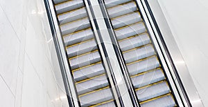 Escalators at an angle in a bright area of a building.
