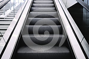 Escalators in big modern area. No people around. Grey tones interior design with shiny glass. Perspective front up down view. Nat