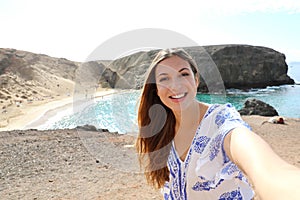 Escape Holidays. Cute young woman smiling with wind in her hair taking selfie on seascape in Lanzarote, Canary Islands