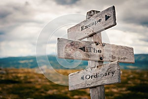 Escape the ordinary text on wooden rustic signpost outdoors in nature/mountain scenery.
