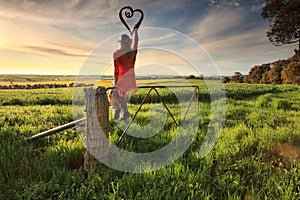 Escape to the Country - female on fence with love heart in morning light