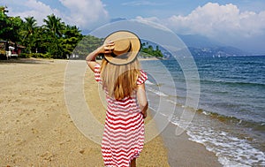 Escape Travel. Young traveler woman walking on empty beach on her resort vacation in Ilhabela Island, Brazil
