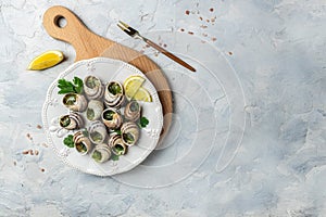 Escargots de Bourgogne Snails with herbs, butter, garlic, glass of white wine on a light background, gourmet food. Restaurant menu