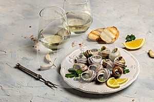 Escargots de Bourgogne or Snails with herbs, butter, garlic on metal plate with forks. wine glass. gourmet food