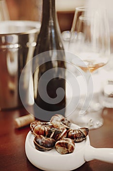 Escargots on white ceramic pan alongside white wine