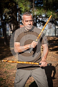 Escrima and kapap instructor demonstrates sticks fighting techniques in park