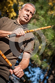 Escrima and kapap instructor demonstrates sticks fighting techniques in park