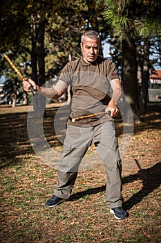 Escrima and kapap instructor demonstrates sticks fighting techniques in park