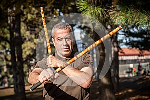 Escrima and kapap instructor demonstrates sticks fighting techniques in park