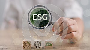 ESG environmental, social, and governance. Magnifying glass focuses ESG icon on the green globe for world sustainable environment