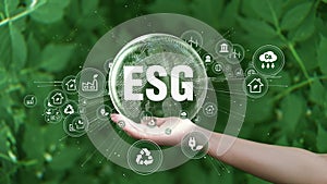 ESG icon concept. Environment, society and governance. Saving the planet in the hands of humans on green background.