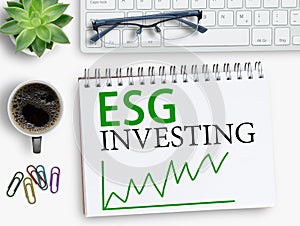 ESG investing results sign on notebook with keyboard and coffee,smartphone,glasses on office desk