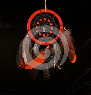 Esoteric and occult still life with red dreamcatcher against black background.