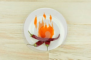 Especially hot sauce: 3 dried chili peppers embraced the painted flames with spicy chili sauce on a white plate on white wooden