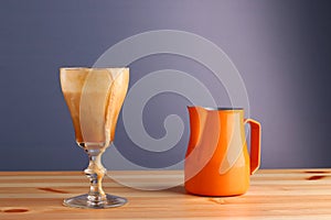 Espesso with ice cream affogato coffee with pitcher on wooden table and grey background. Coffee cold drink with vanilla ice cream