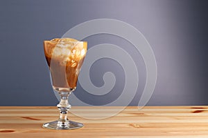 Espesso with ice cream affogato coffee on wooden table and grey background. Coffee cold drink with vanilla ice cream and espresso