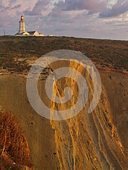 Espichel cape lighthouse sitting on top of a cliff during sunset. Sesimbra, Portugal