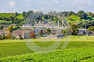 Esplanade with green grass on Caestert plateau, suspension bridge and Kanne village in background