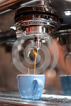 Espresso being made and put into a blue demitasse