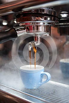 Espresso being made and put into a blue demitasse