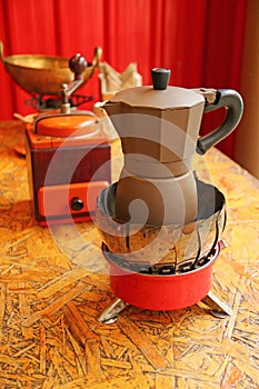 Espresso Coffee Being Brewed in a Moka Pot with a Wooden Retro Coffee Grinder in Background