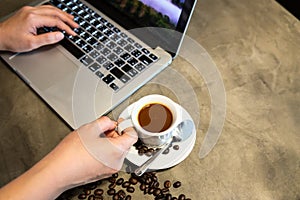 Espresso coffee in a cup of hot coffee and coffee beans,woman hands is working,using a computer,girl fingers typing on the