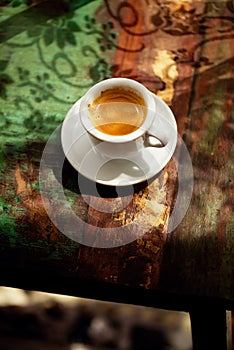 Espresso coffee cup on rustic table with sun