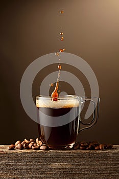 Espresso coffee glass cup with splashes on a brown background