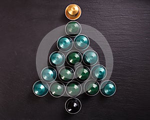 Espresso coffee pods forming a christmas tree, on black background, top view