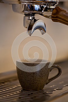 Espresso coffee pouring into ceramic cup, closeup