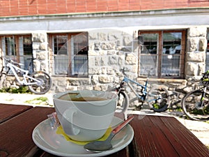 Espresso káva na stole s bicyklami na pozadí pri chate.