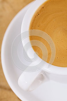 Espresso coffee in thick white cup, on wood photo