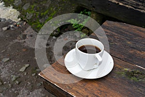 Espresso coffee in white ceramic mug on a traditional brown wooden table.