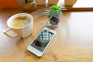 Espresso coffee in white cup with smartphone with copy space