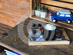 Espresso con panna in Black and white cup on wooden table with natural light.