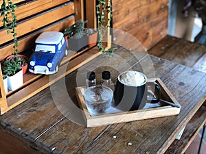 Espresso con panna in Black and white cup on wooden table with natural light.