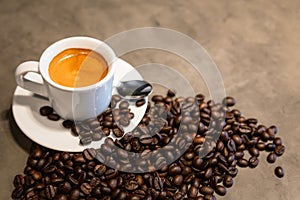 Espresso in a cup of hot coffee and coffee beans on concrete polishing floors cement background in loft style in a cafe shop,